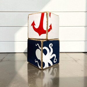 Couple of  Coastal Anchor Tissue Box Covers arranged on a shelf in a coastal vacation rental, featuring hand-painted nautical anchor design for beach cottages, seaside vacation homes, coastal décor, or short-term rental interiors, perfect for coordinated bedrooms, bathrooms