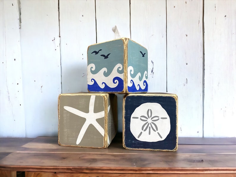 Coastal beach house tissue box covers featuring starfish, sand dollar, and ocean wave designs displayed together, distressed wood finish for relaxed beach decor, perfect for beach houses, coastal cottages, lake homes, and vacation rentals, ocean-inspired home accent handmade in Maine
