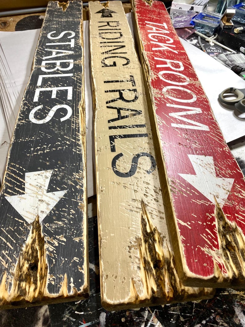 Tack Room Equestrian Sign Set displayed flat on a table, showing all three hand-distressed wood signs together. Perfect for Western barn, ranch, or rustic cabin décor, ideal for tack rooms, stables, vacation rentals, and lodge-style interiors. Highlights authentic hand-painted lettering, rustic wood textures, and Western character