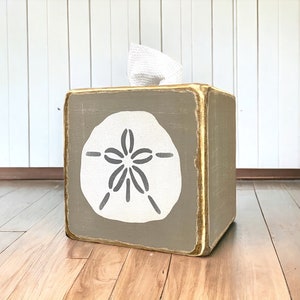 Khaki sand dollar tissue box cover photographed in a studio setting, coastal beach house decor with ocean-inspired sand dollar artwork, rustic distressed wood tissue box for beach cottages, seaside bathrooms, vacation rentals, and relaxed coastal interiors