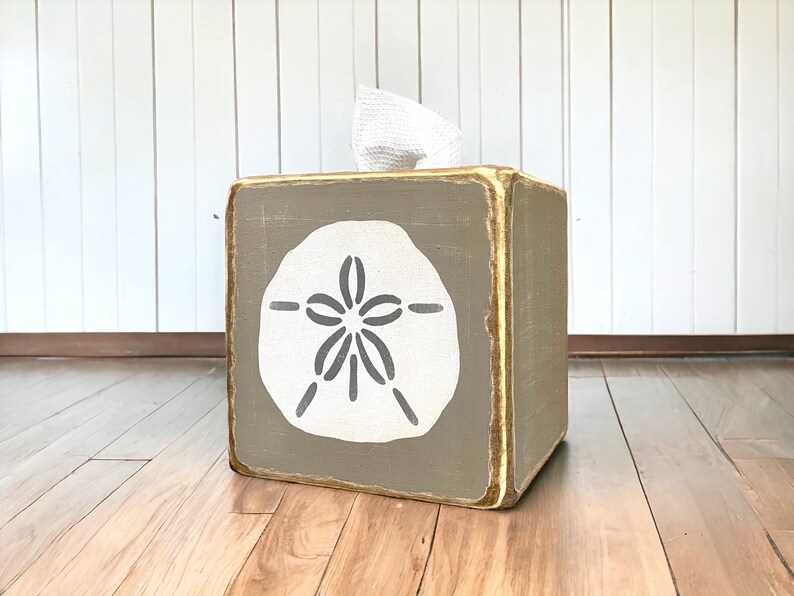 Khaki sand dollar tissue box cover photographed in a studio setting, coastal beach house decor with ocean-inspired sand dollar artwork, rustic distressed wood tissue box for beach cottages, seaside bathrooms, vacation rentals, and relaxed coastal interiors