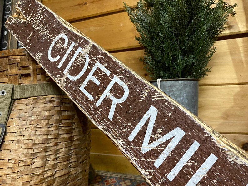 Close-up of the handcrafted Cider Mill wood sign highlighting hand-painted lettering, rich wood grain, layered paint, and vintage distressing inspired by historic apple orchards, country farm signs, and timeless fall decor.