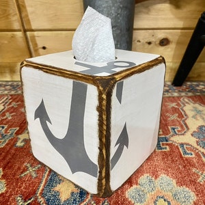 Coastal Anchor Tissue Box Covers displayed on a rustic coastal shelf in a beach cottage or vacation rental, hand-painted nautical anchors ideal for beach cottage décor, coastal vacation homes, seaside cabins, or short-term rental interiors, perfect for bedrooms, bathrooms, or living spaces