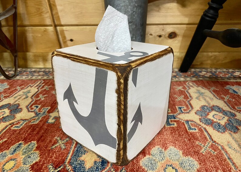Coastal Anchor Tissue Box Covers displayed on a rustic coastal shelf in a beach cottage or vacation rental, hand-painted nautical anchors ideal for beach cottage décor, coastal vacation homes, seaside cabins, or short-term rental interiors, perfect for bedrooms, bathrooms, or living spaces