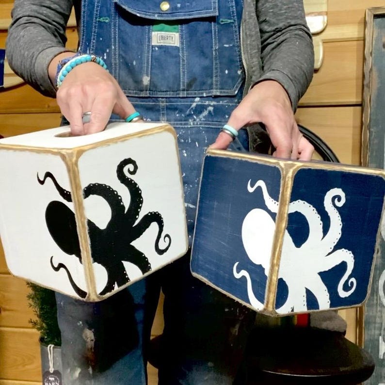 Artist holding a handcrafted octopus tissue box cover showcasing authentic American-made craftsmanship, hand painted sea life artwork, vintage distressing, and small-batch artistry inspired by the coast