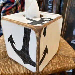 Anchor Tissue Box Cover displayed on a coastal shelf in a seaside vacation rental, showing hand-painted nautical anchor design for beach cottages, coastal homes, nautical décor, or short-term rental interiors, perfect for bedrooms, bathrooms, or living areas