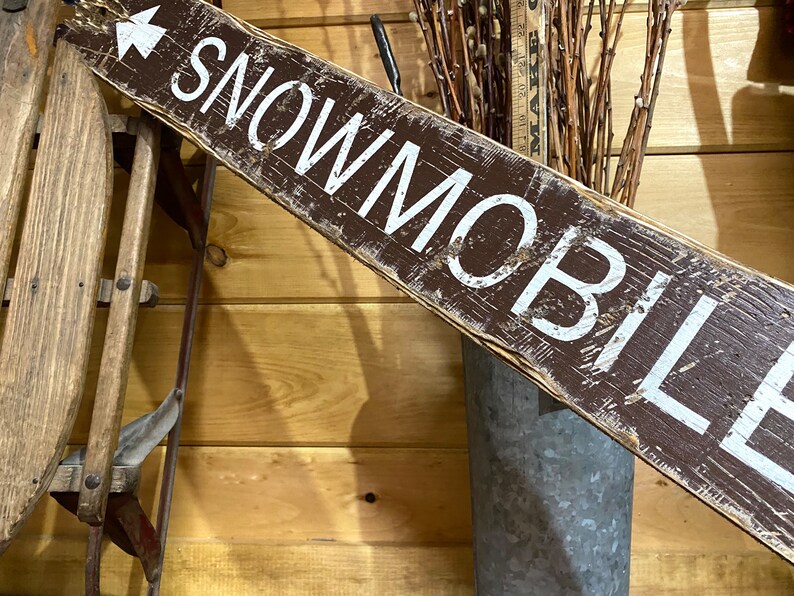 Close-up of hand-painted lettering on a Snowmobile Trails Directional Sign, highlighting the detailed craftsmanship, weathered rustic finish, and northern trail-inspired design, ideal for cabins, lodges, or winter vacation homes