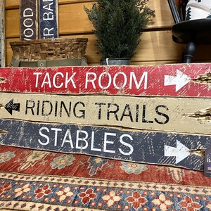 Tack Room Equestrian Sign Set displayed in a Western rustic cabin, showing hand-distressed wood signs styled above a tack room or stable area. Perfect for horse lovers, equestrian enthusiasts, vacation rentals, ranch homes, and cabin décor, highlighting authentic handcrafted style, Western character, and rustic charm