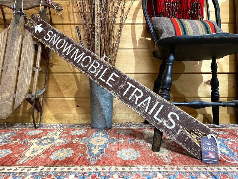 Snowmobile Trails Directional Sign, rustic wooden cabin décor hand-painted and distressed, perfect for northern lodge, mountain cabin, man cave, or winter vacation home. Captures the charm of snowmobiling adventures, fresh winter trails, and outdoor recreation, adding cozy, rustic character to ski chalets, cabins, and lodges. Handmade in Maine, showcasing artisan craftsmanship for snow and winter sports enthusiasts