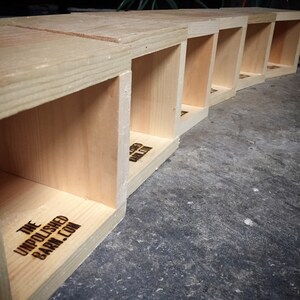 Row of unfinished wooden tissue box covers showing raw materials and handcrafted construction, highlighting quality woodworking, solid wood craftsmanship, and made-to-order process for rustic cabin, coastal, and lake house decor