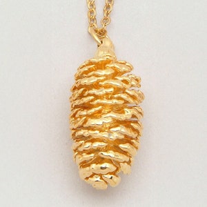 May include: A gold-tone necklace with a detailed pine cone pendant.