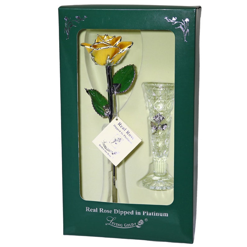 May include: A single yellow rose dipped in platinum, preserved in a clear glass vase. The rose and vase are displayed in a green box with the words "Real Rose Dipped in Platinum" and "Living Gold!" printed on the front.