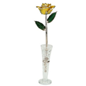 May include: A single, gold-plated rose with green leaves, displayed in a clear glass vase with a cut-glass design.