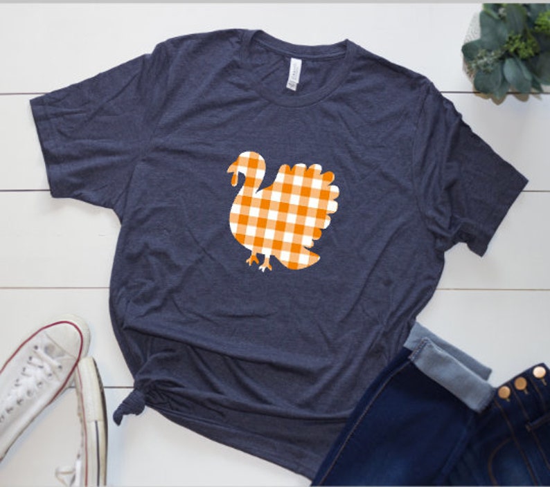 May include: A navy blue t-shirt with a white and orange gingham turkey design.
