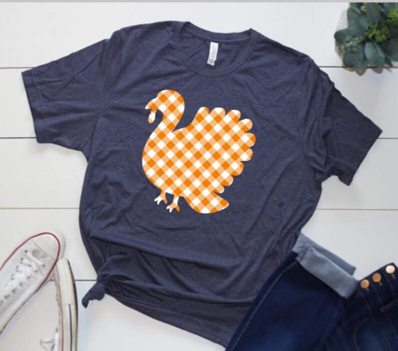 May include: A navy blue t-shirt with a white and orange gingham turkey design.