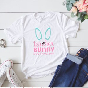 May include: White t-shirt with a pink and blue design that says "teacher bunny" with the name "Miss Smith" underneath.