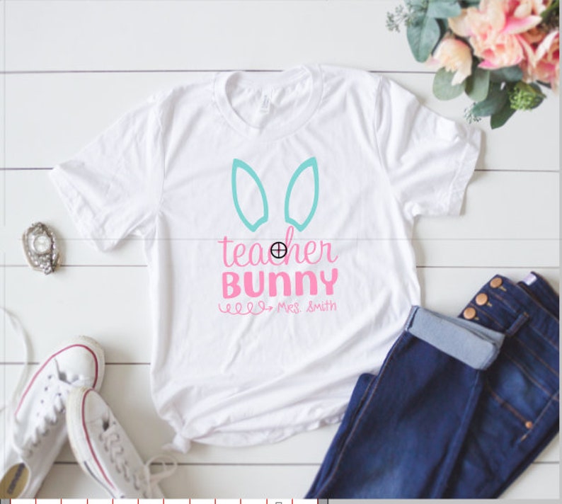 May include: White t-shirt with a pink and blue design that says "teacher bunny" with the name "Miss Smith" underneath.