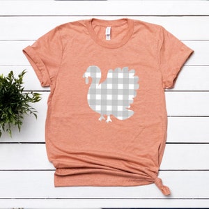 May include: A peach colored t-shirt with a white gingham turkey design.