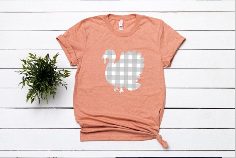 May include: A peach colored t-shirt with a white gingham turkey design.