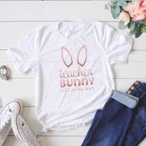 May include: White t-shirt with a rose gold bunny ear design and the text "teacher bunny" and "Mrs. Smith".