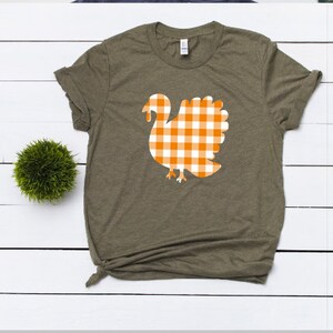 May include: A green t-shirt with a white and orange checkered turkey design.