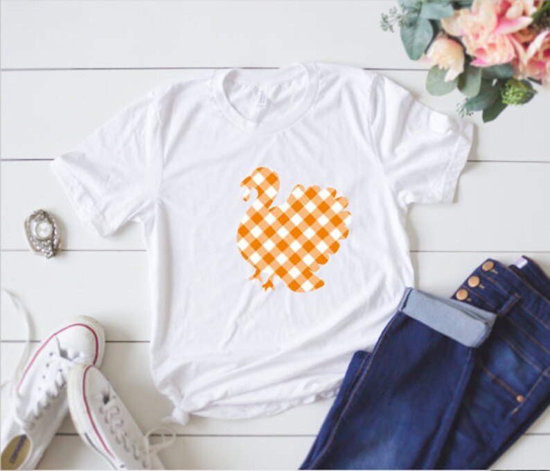 May include: White t-shirt with an orange and white gingham turkey design.