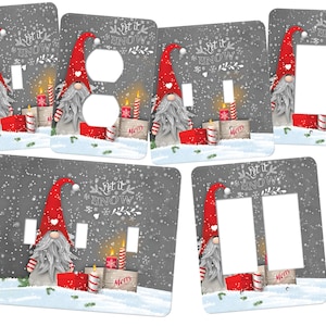 May include: Set of five light switch and outlet covers featuring a winter gnome design. The covers are gray with a white snowy background and a gnome with a red hat and white beard. The text "Let it Snow" is written in white on the covers.