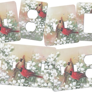 May include: Set of six light switch and outlet covers featuring a pair of red cardinals perched on a branch with white dogwood blossoms. The covers are printed with a realistic painting of the birds and flowers.