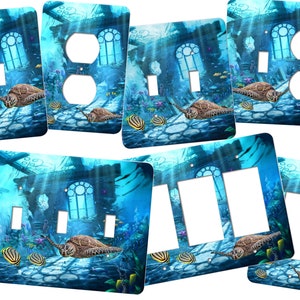 May include: Set of six light switch and outlet covers featuring an underwater scene with a sunken building, sea turtles, and tropical fish. The covers are printed with a blue, green, and brown color scheme.