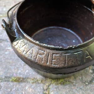 May include: A black cast iron pot with a handle and the word "MARIETTA" embossed on the side.