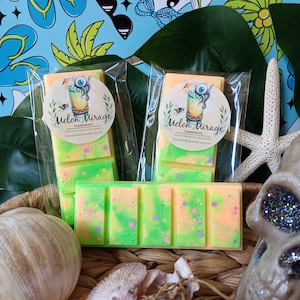 May include: Wax melt bars in clear packaging, with a green and orange color scheme, and a label that reads "Melon Mirage". The bars are displayed with seashells, a starfish, and a skull. The background features a blue pattern with beach-themed illustrations.