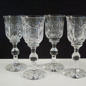 May include: Set of four clear glass shot glasses with a cut glass design. The glasses have a round bowl and a tall stem.