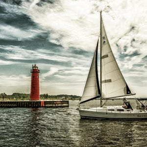 May include: A sailboat with white sails glides on the water near a red lighthouse. The sky is filled with dramatic clouds. The scene evokes a sense of tranquility and maritime adventure.