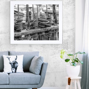 Pu&ograve; includere: Stampa incorniciata in bianco e nero di corde e sartiame nautico. L'immagine presenta corde avvolte attorno a pali di legno, con altre corde appese sullo sfondo. La fotografia &egrave; esposta sopra un divano grigio.