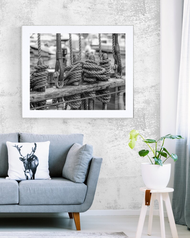Pu&ograve; includere: Stampa incorniciata in bianco e nero di corde e sartiame nautico. L'immagine presenta corde avvolte attorno a pali di legno, con altre corde appese sullo sfondo. La fotografia &egrave; esposta sopra un divano grigio.