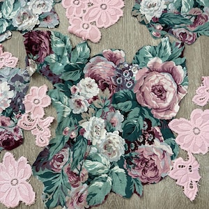May include: A collection of floral fabric cutouts featuring dark green, teal, and dusty rose pink roses, accompanied by several light pink lace flower appliqués. A yellow measuring tape is positioned at the bottom, showing a width of 24 inches.