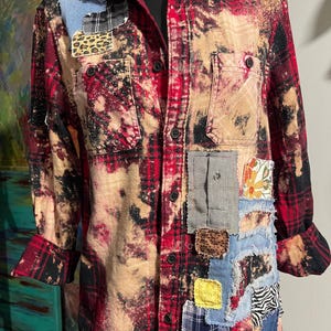Peut inclure: Chemise à carreaux rouge et noir avec effet de décoloration et détails patchwork. Les patchs incluent du denim, des imprimés léopard et des tissus floraux. Comprend deux poches de poitrine et des boutons noirs. Vêtement unique et recyclé.