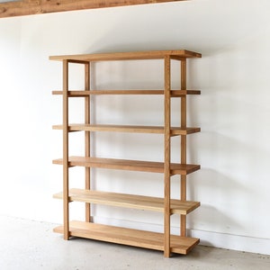May include: A wooden bookshelf with five shelves and a simple, modern design. The shelves are made of solid wood and have a natural finish.