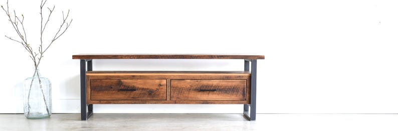 May include: A rustic wooden TV stand with two drawers and a metal frame. The stand has a natural wood finish and a distressed look.