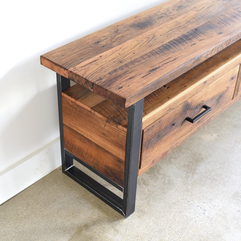 May include: A rustic wooden media console with two drawers and a black metal frame. The console has a distressed wood finish and a simple design.