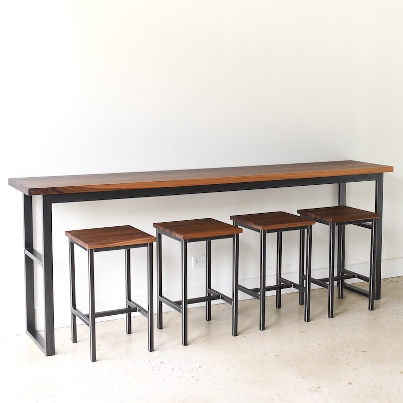 May include: A long, rectangular wooden table with a black metal frame and four matching wooden stools with black metal frames. The table and stools are all made of dark wood.