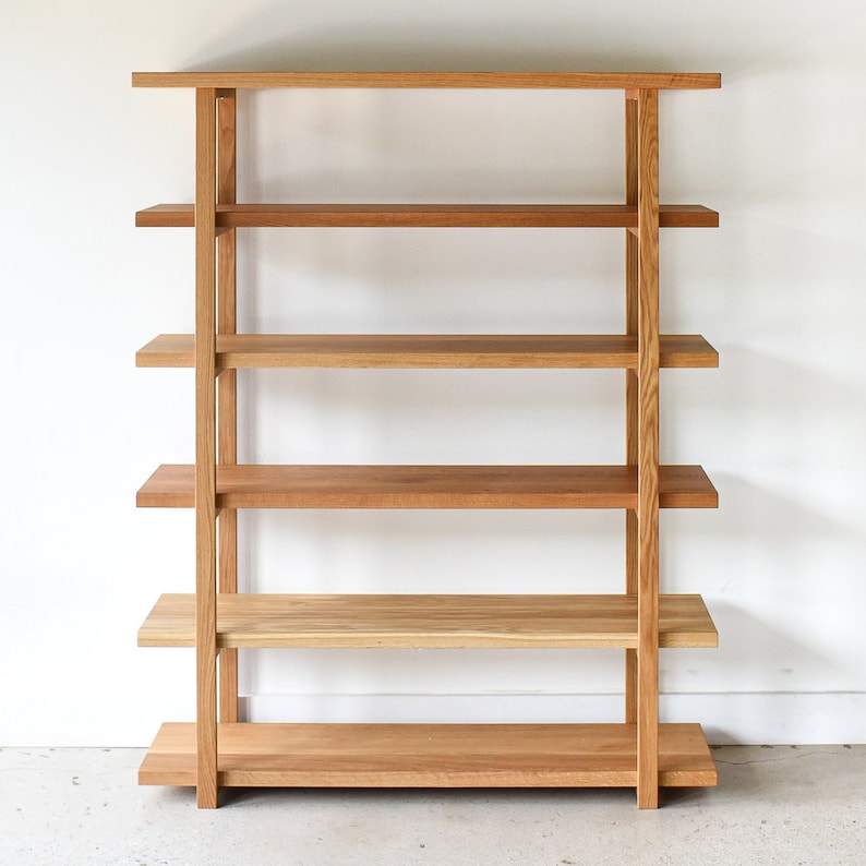 May include: A wooden bookshelf with five shelves. The bookshelf is made of light brown wood and has a simple, modern design.