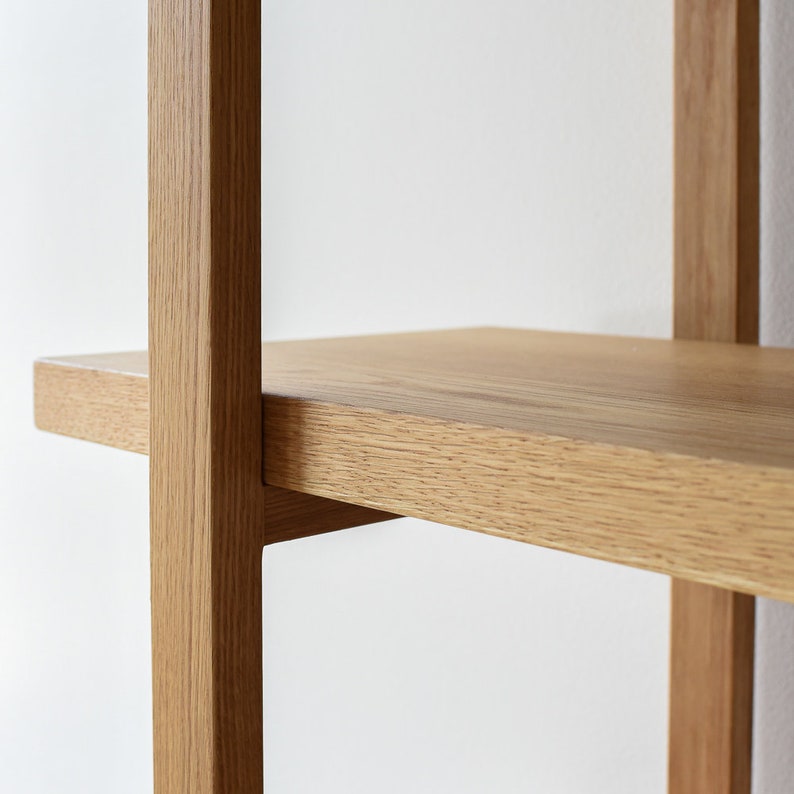 May include: Close-up of a wooden shelf unit with a light brown finish. The shelf is made of solid wood and has a simple, modern design.