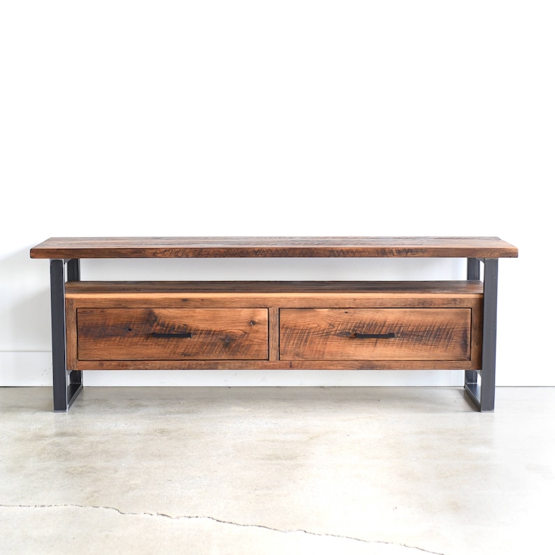 May include: A rustic wooden media console with two drawers and a lower shelf. The console has a dark brown wood finish and black metal legs.