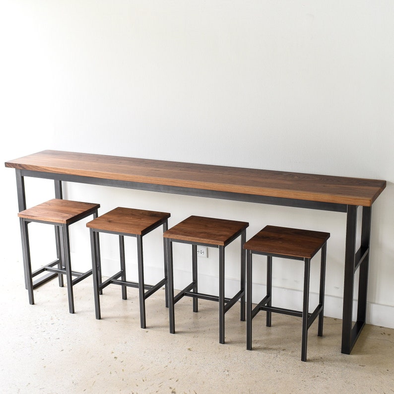 May include: A long, rectangular wooden table with a black metal frame and four matching wooden stools with black metal frames. The table and stools are all made of dark wood.