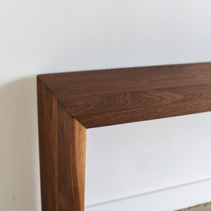 May include: A dark brown wooden console table with a rectangular top and a simple, modern design.