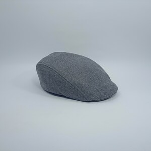 May include: A gray wool flat cap with a slightly curved brim.