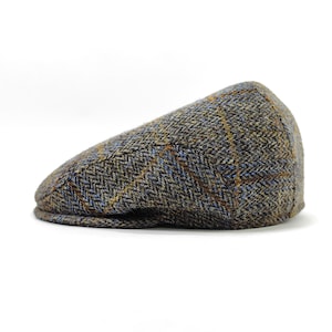 May include: A tweed flat cap in shades of brown, blue, and yellow. The cap features a classic herringbone pattern and a rounded shape. This stylish hat is a traditional accessory.