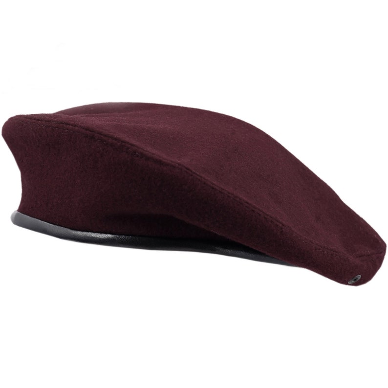 Pu&ograve; includere: Un berretto di lana color bordeaux con una fascia in pelle nera attorno al bordo.
