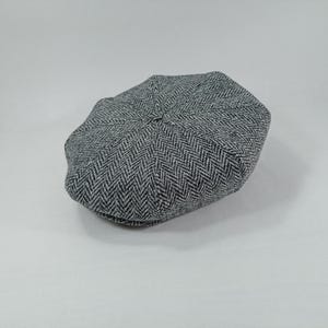 May include: A gray and black herringbone patterned newsboy cap.